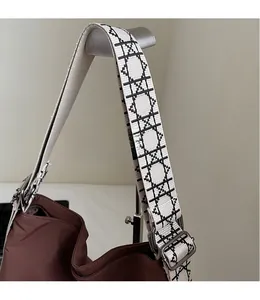 Detail of adjustable wide jacquard strap on brown canvas shoulder bag with silver buckle