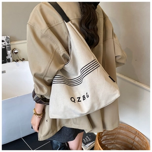 Detailed close-up of a large beige canvas tote bag with black stripes and QZBG logo lettering