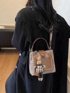 Retro brown bucket bag with textured leather, gold studs, and stylish checkered strap