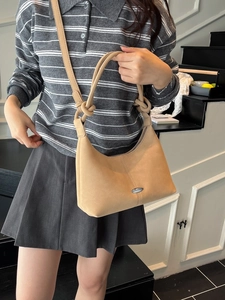 Beige soft suede hobo bag with knotted strap and metal buckle detail shown on model