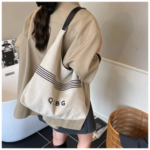 Detailed back view of a large beige canvas tote bag with black stripes and leather straps