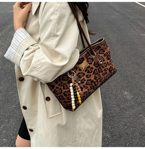 Detail of leopard print shoulder bag with gold hardware and colorful beaded keychain