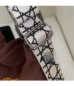 Detail of silver metal buckle and embroidered logo shoulder strap on the coffee bag