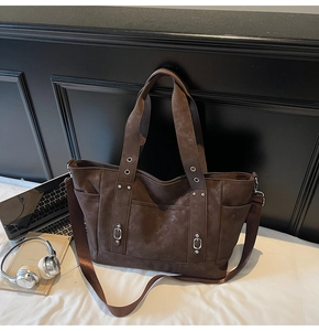 Detailed view of vintage dark brown tote bag with metal rivets and wide shoulder strap