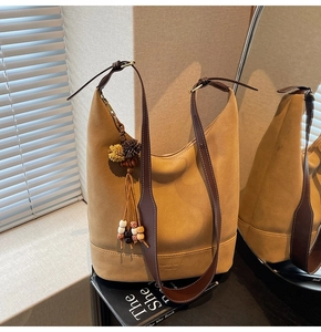 Gros plan du sac seau en daim mat avec bandoulière en cuir et détails de glands
