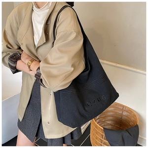 Detail of black canvas tote bag showing the QZBG 3D embroidery and durable fabric texture