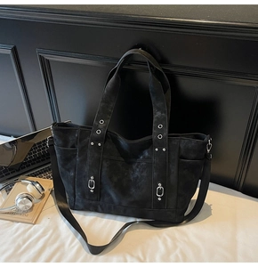 Close-up of black canvas tote bag showing silver rivets and side pockets for commute