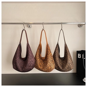 Three stylish leopard print tote bags in brown, yellow, and khaki hanging on display