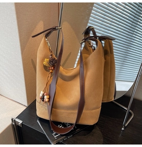 Détails du sac seau marron mat avec pompon bohème et gaufrage de marque élégant