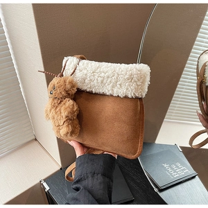 Dettaglio della borsa a secchiello in camoscio marrone con bordo in sherpa bianco e orso