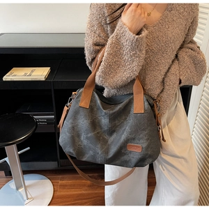 Close-up of retro charcoal tote bag with brown straps in a cozy indoor setting