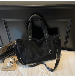 Detail shot of black vintage tote bag featuring decorative rivets and side pockets