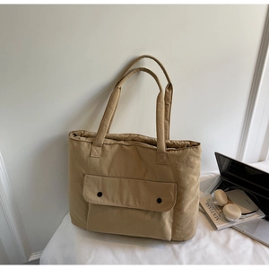 Close-up of khaki tote bag with front pocket, featuring double snaps and durable fabric
