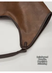 Detail of reinforced handle attachment and precise stitching on brown leather tote bag