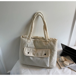 Detailed view of large quilted canvas tote bag with snap pocket and laptop storage