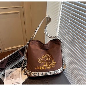 Detail of embroidered elephant pattern on brown canvas bucket bag with woven straps
