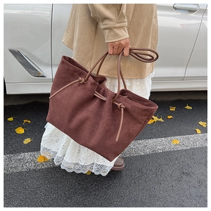 Detailed view of the large dark brown suede tote bag in a casual outdoor setting