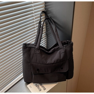 Close-up of black canvas tote bag with flap pocket and long straps in natural light