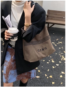 Detail of a brown canvas tote bag with black stripes and embroidery on a female model