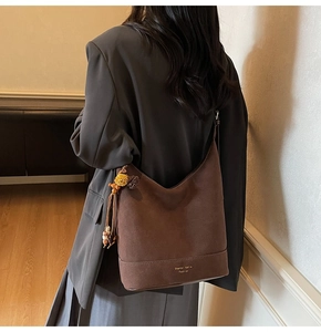 Vue détaillée du sac seau en daim mat café avec breloques décoratives en peluche