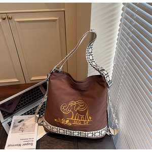 Detail of dark brown nylon bucket bag with elephant embroidery and woven geometric strap