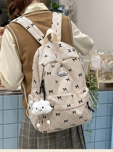 Detail of cream corduroy backpack with bow pattern and plush cloud charm on a model