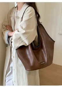 Close-up of deep brown Hobo bag with PANTOOR logo worn over a classic beige trench coat