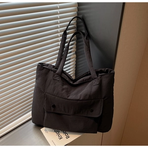 Detail of black quilted canvas tote bag with large front flap pocket and sturdy shoulder straps