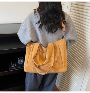 Detail of ginger tote bag showing wide handles and metal ring buckle with side pocket