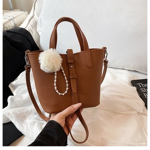 Borsa a secchiello marrone con grana litchi decorata con pompon e ciondolo a perla