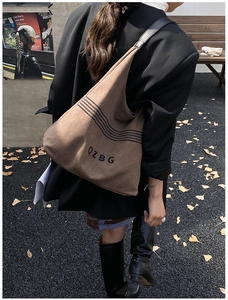 Street view of large brown canvas tote bag with black embroidery and letter print