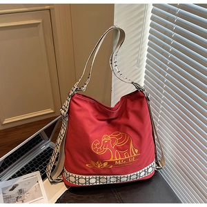 Detail of red canvas tote bag with golden elephant embroidery and geometric strap