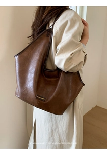 Detail showing high-capacity brown tote bag with premium leather texture and logo