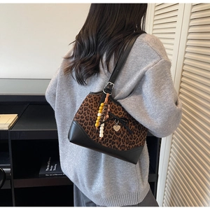 Detail of leopard print tote bag featuring wooden beads and black bow tie on model