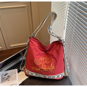 Detail of red canvas tote bag with yellow elephant embroidery and geometric shoulder strap