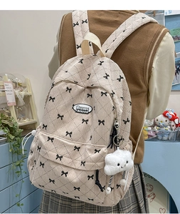 Detail of beige corduroy backpack with black bow patterns and cloud plush pendant