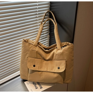 Detail of camel canvas tote bag showing the front flap pocket and durable fabric texture