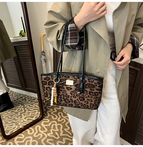 Detail of leopard print tote bag with beaded tassel charm and metallic logo plate