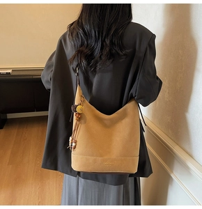 Gros plan d'un sac cabas en daim camel avec pompon rétro et perles en bois sur la bandoulière