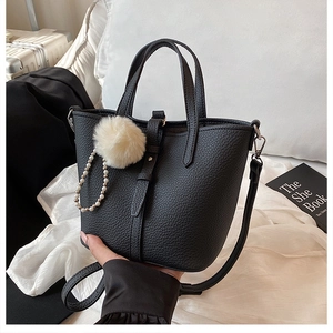 Dettaglio borsa a secchiello in pelle martellata nera con pompon e catena di perle