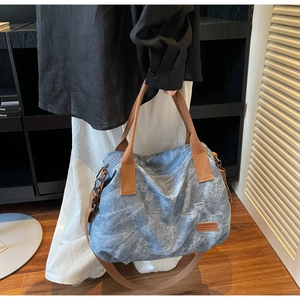 Close-up of washed blue-grey canvas tote with vintage texture and brown straps