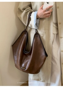 Detail of deep brown leather hobo bag with oil wax texture and minimalist brand label