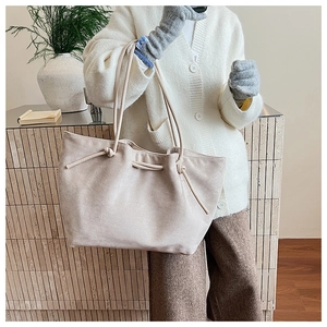 Detail of soft beige suede tote bag with drawstring knot and thin shoulder strap