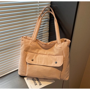 Detail of high-capacity beige canvas tote bag featuring double-buckle front pocket