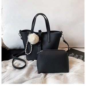 Dettaglio borsa shopper nera a grana litchi con ciondolo peluche e catena di perle