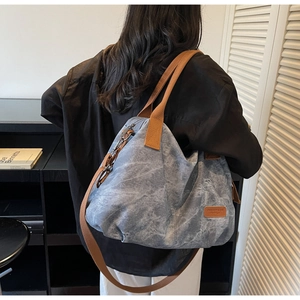 Detail view of vintage blue canvas tote bag with brown woven straps and leather logo patch