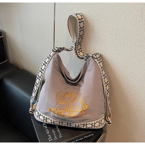 Detail of embroidered elephant logo and woven strap on a purple canvas bucket bag