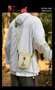 Détail du sac bandoulière beige avec sangle vert fluo et poche avant à cordon