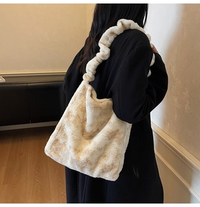 Close-up of beige plush shoulder bag worn by model over black coat for winter style