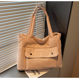 Detail of light pink canvas tote bag showing front flap pockets with black snap buttons
